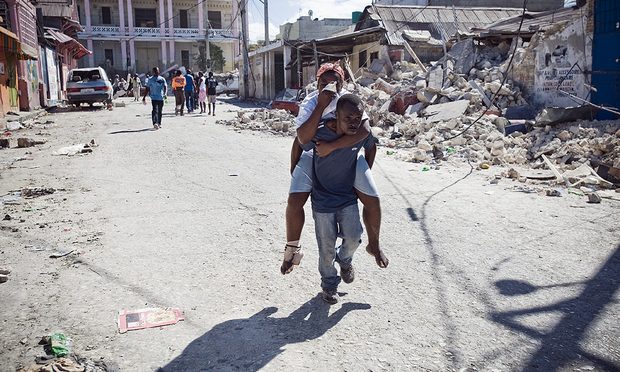 Man carries a woman to a makeshift clinic on his back on Saturday January 16, 2010 in Port-au-Prince, Haiti.