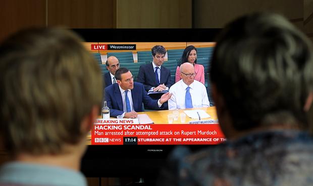 A family in Stockport, England, watch a television showing News Corporation Chief Rupert Murdoch and his son James testifying before Parliament. A family in Stockport, England, watch a television showing News Corporation Chief Rupert Murdoch and his son James testifying before Parliament.