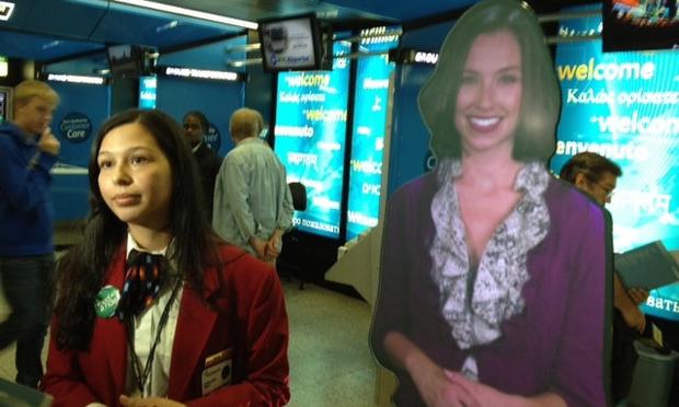 A human customer service representative talks to reporters at LGA airport. To her left is a newly unveiled customer service avatar.