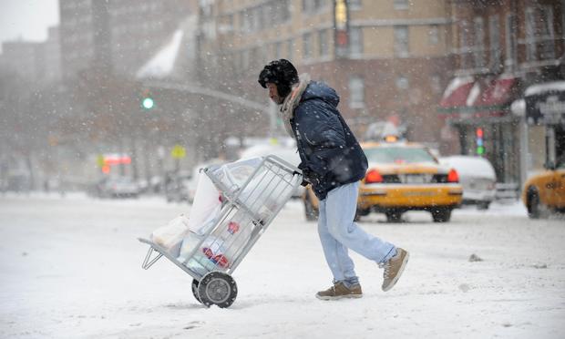 A delivery man crosses Third Avenue on the east side of Manhattan January 21, 2012 during the first snow storm of the year in New York.