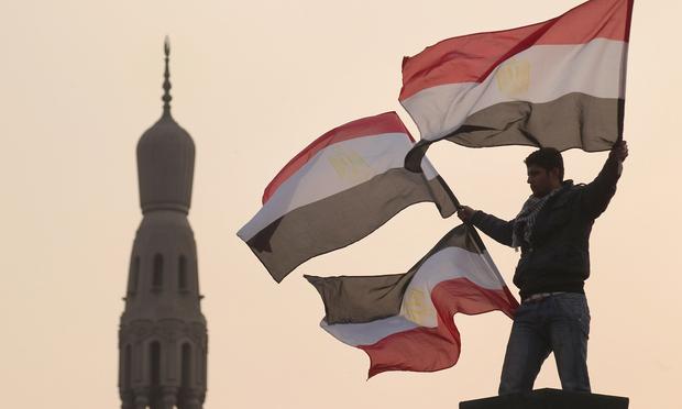 A youth waves Egyptian flags from a lamp post in Tahrir Square on February 1, 2011 in Cairo, Egypt. A youth waves Egyptian flags from a lamp post in Tahrir Square on February 1, 2011 in Cairo, Egypt.