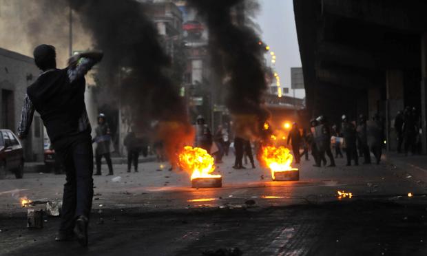 Egyptian riot police gather near burning tires as a demonstrator throws an object towards them during a protest in Cairo, Egypt on January 26, 2011 Egyptian riot police gather near burning tires as a demonstrator throws an object towards them during a protest in Cairo, Egypt on January 26, 2011