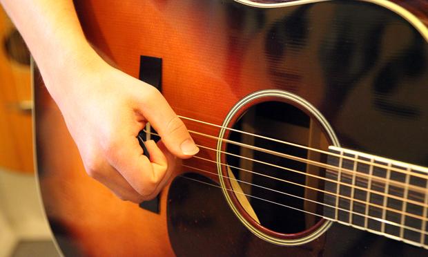 Joe Fox strumming a guitar at Mandolin Brothers.