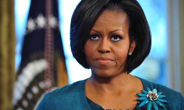 First Lady Michelle Obama looks on as US President Barack Obama speaks before signing a memorandum on childhood obesity February 9, 2010 in the Oval Office
