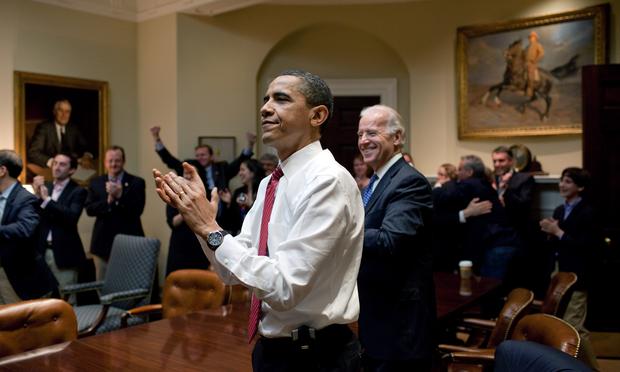 U.S. President Barack Obama, Vice President Joe Biden, and senior staff applaud in the Roosevelt Room of the White House, as the House of Representatives passes the health care reform bill.