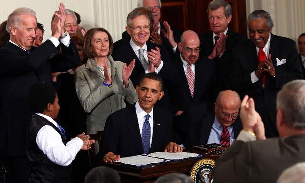 U.S. President Barack Obama (C) is applauded after signing the Affordable Health Care for America Act during a ceremony with fellow Democrats in the East Room of the White House