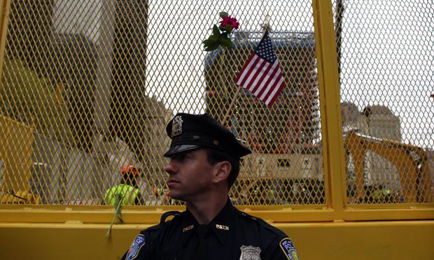 Police officers stand guard at the World Trade Center site where flowers and flags have been left by visitors.