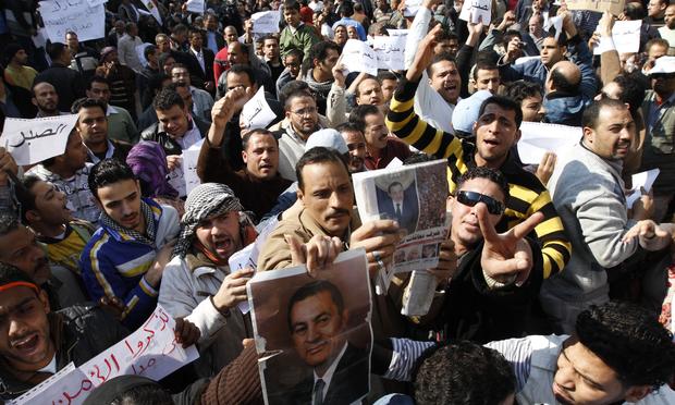 Supporters of Egyptian President Hosni Mubarak shout slogans and hold signs during a rally to show their allegiance for the embattled leader in Cairo on February 2, 2011.