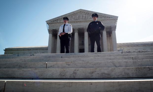 Two policemen guard outside the US Supreme Court on the third day of oral arguements over the constitutionality of the Patient Protection and Affordable Care Act on March 28, 2012 in Washington, DC.