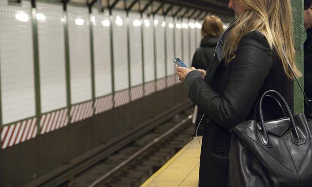 A woman uses her smartphone while waiting for the train in the Times Square subway station. A woman uses her smartphone while waiting for the train in the Times Square subway station.