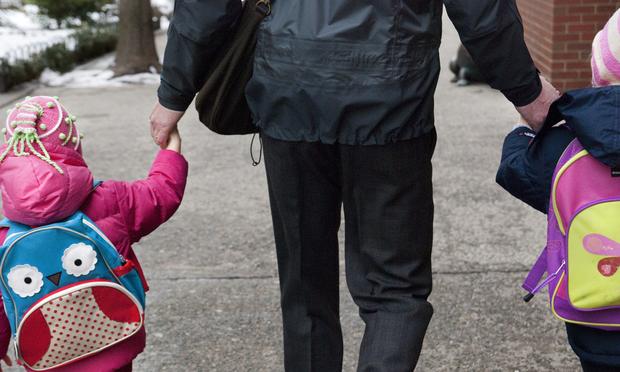 A man holds the hands of two young girls as they walk to P.S. 234 elementary school in Lower Manhattan.