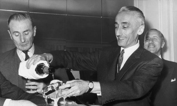 Jacques Cousteau (1910 - 1997) dousing a new type of underwater camera, the 'Calypso Phot,' with champagne at its unveiling ceremony, December 4, 1962.