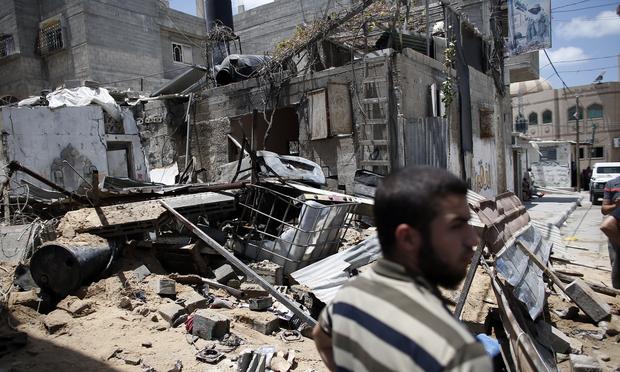 A Palestinian Hamas member stands guard in front of a destroyed building following an Israeli air strike on July 14, 2014 in Gaza City.