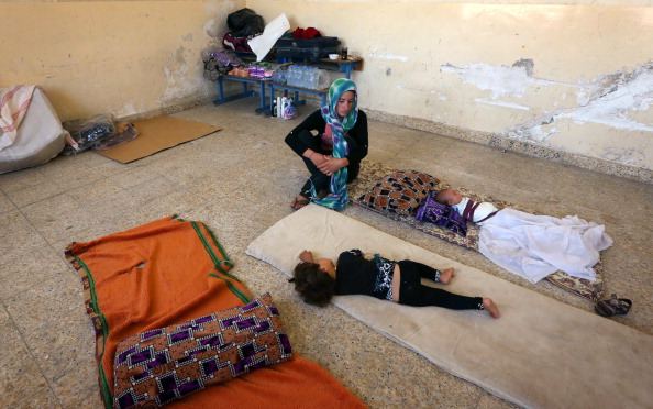 An Iraqi Yazidi mother who fled the violence in the northern Iraqi town of Sinjar, sits with her children at a school where they are taking shelter in the Kurdish city of Dohuk.