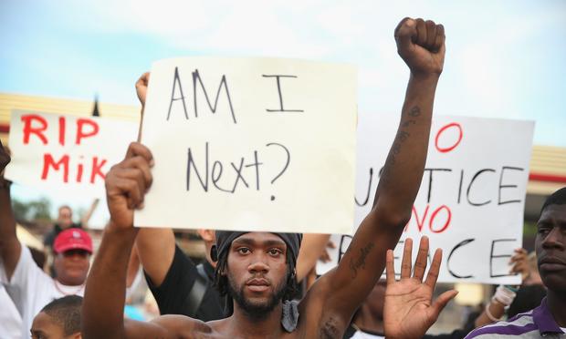 Demetrus Washington joins other demonstrators protesting the shooting death of teenager Michael Brown on August 14, 2014 in Ferguson, Missouri.