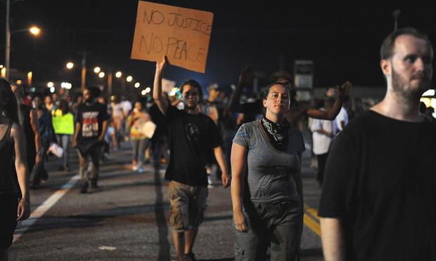 Demonstrators display signs during a protest on West Florissant Avenue in Ferguson, Missouri on August 18, 2014.