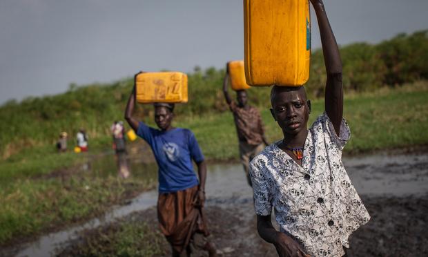 Women and children carry water in Minkammen on 01/08/14. Unrest began on 12/15/13 as a clash between army units loyal to South Sudan's President Salva Kiir and those loyal to ex-VP Riek Machar.