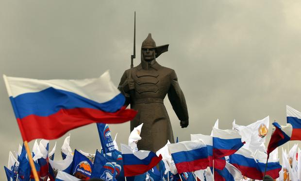 Pro-Kremlin activist hold Russian flags near a monument to Red Army soldier as they rally in the southern Russian city of Stavropol, on March 18, 2014, to celebrate the incorporation of Crimea.
