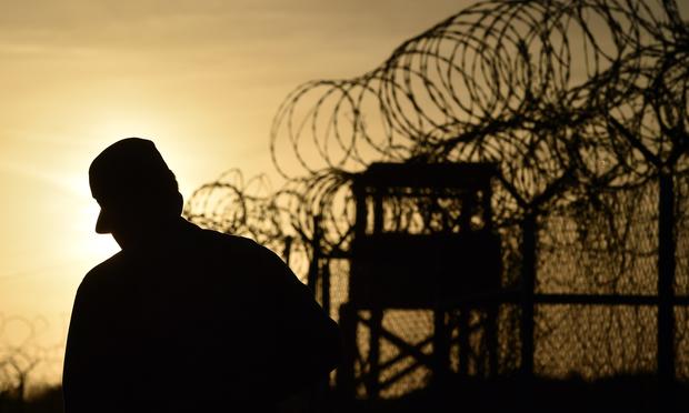 A U.S. soldier walking next to the razor wire-topped fence at the abandoned 'Camp X-Ray' detention facility at the US Naval Station in Guantanamo Bay, Cuba, April 9, 2014.