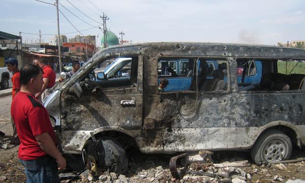 An Iraqi man looks at a destroyed mini bus at the site of car bomb attack in the northern city of Kirkuk on June 4, 2014.