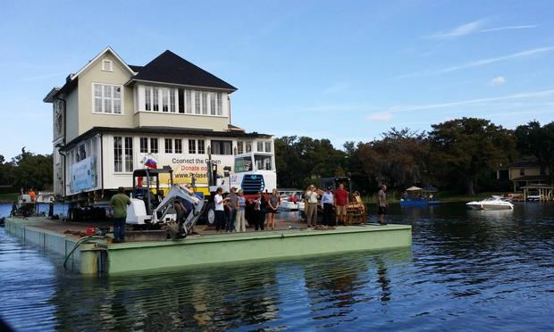 Onlookers watched as the first half of the Capen House, built in 1885, made its way across Lake Osceola to its new home