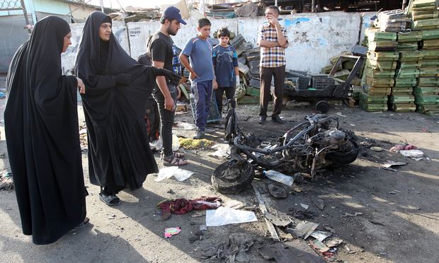 Iraqi onlookers gather on July 16, 2014 around a burnt motorcycle at the scene of an explosion that took place the previous night in Sadr City, one of Baghdad's northern Shiite-majority districts. Iraqi onlookers gather on July 16, 2014 around a burnt motorcycle at the scene of an explosion that took place the previous night in Sadr City, one of Baghdad's northern Shiite-majority districts.