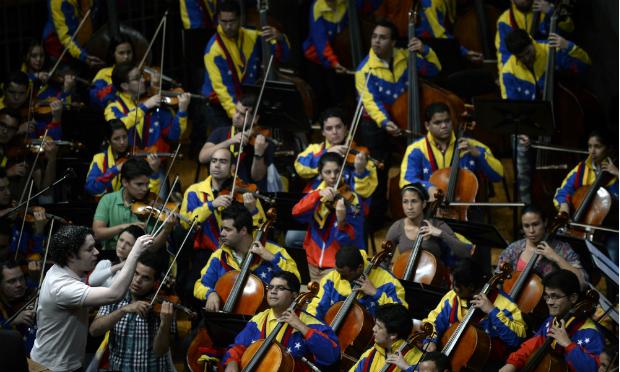 Gustavo Dudamel conducts the Simon Bolivar Symphony Orchestra at a swearing-in ceremony of the new ministers in Caracas in 2013. Gustavo Dudamel conducts the Simon Bolivar Symphony Orchestra before the beginning of the swearing-in ceremony of the new ministers in Caracas, on April, 22, 2013.