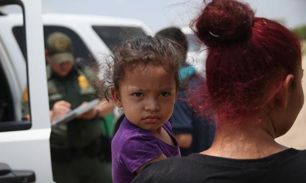 July, 24, 2014 A mother and child, 3, from El Salvador await transport to a processing center for undocumented immigrants after they crossed the Rio Grande into the United States in Mission, Texas