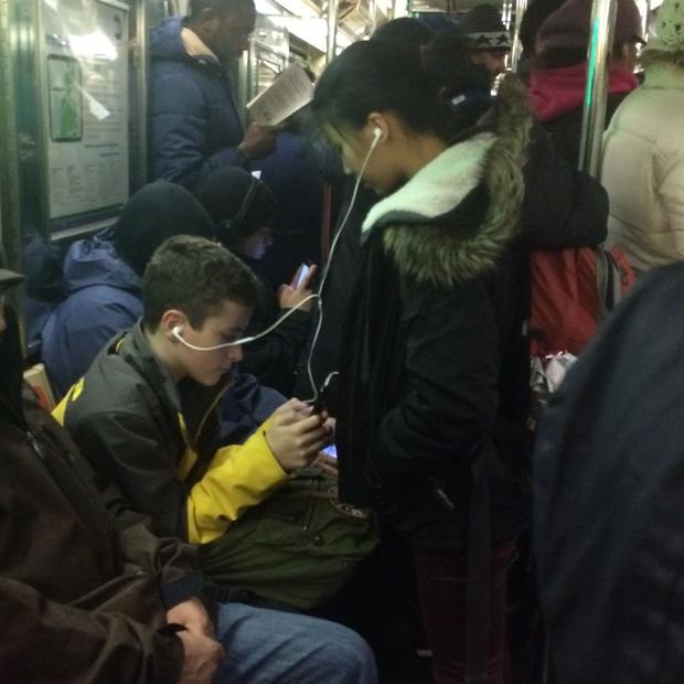 couple sharing headphones on subway