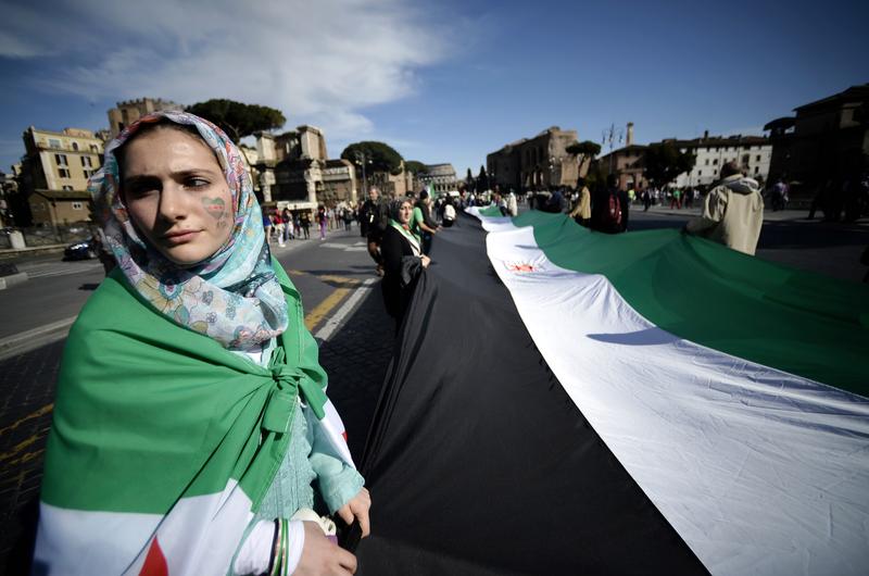 Demonstrators hold a large Syrian National Coalition flag as they rally against Syrian President Bashar al-Assad in downtown Rome on April 13, 2013.