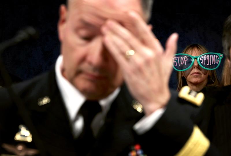 Medea Benjamin of CodePink protests as Director of the NSA Gen. Keith Alexander (L) waits for the beginning of a hearing before the House (Select) Intelligence Committee October 29, 2013.