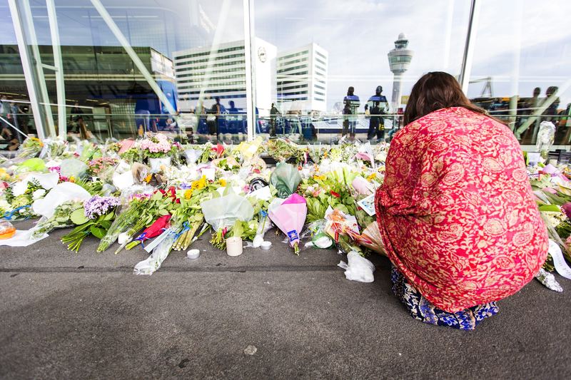 A woman kneels by flowers layed at a remembrance spot at Schiphol Airport, near Amsterdam, July 20, 2014. Malaysia Airlines flight MH17, which took off at Schiphol airport, was blown out of the sky.