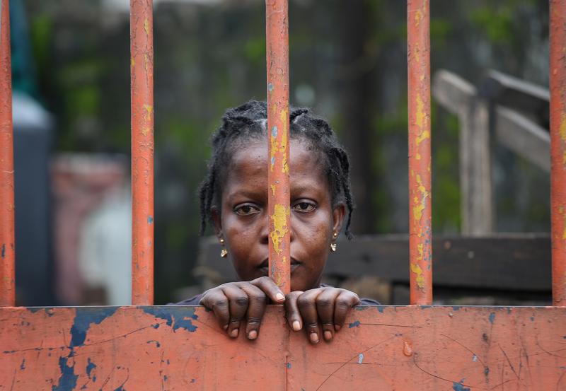 A West Point slum resident looks from behind closed gates on the second day of the government's Ebola quarantine on their neighborhood on August 21, 2014 in Monrovia, Liberia.