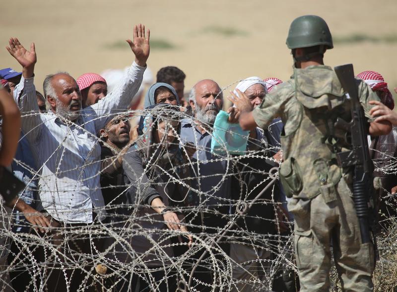 Syrians fleeing from clashes between ISIS militants and Democratic Union Party (PYD) forces in the Ar-Raqqah Governorate of Syria, wait at the Turkish-Syrian border. Sept. 19, 2014