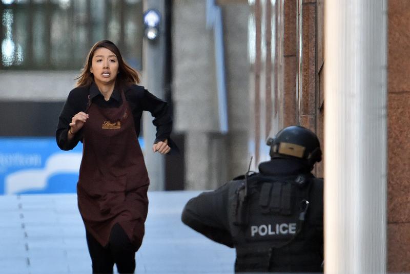 One of the hostages runs towards police from a cafe in the central business district of Sydney on December 15, 2014.