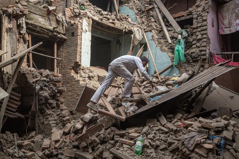 A man climbs on top of debris after buildings collapsed on April 26, 2015 in Bhaktapur, Nepal, after a major 7.8 earthquake hit Kathmandu mid-day on Saturday.