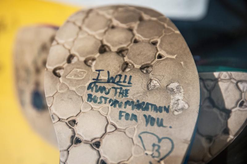 A runner's shoes read, 'I will run the Boston Marathong for you,' in a display titled, 'Dear Boston: Messages from the Marathon Memorial' in the Boston Public Library. April 14, 2014