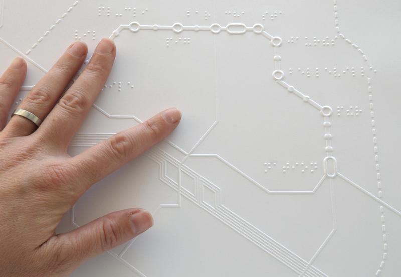 A person touches a braille map of the Parisian metro