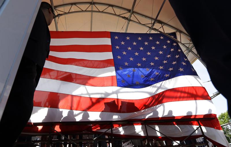 People standing behind Republican presidential candidate Donald Trump are seen in silhouette against a large American flag from backstage Saturday, May 7, 2016, in Lynden, Wash.