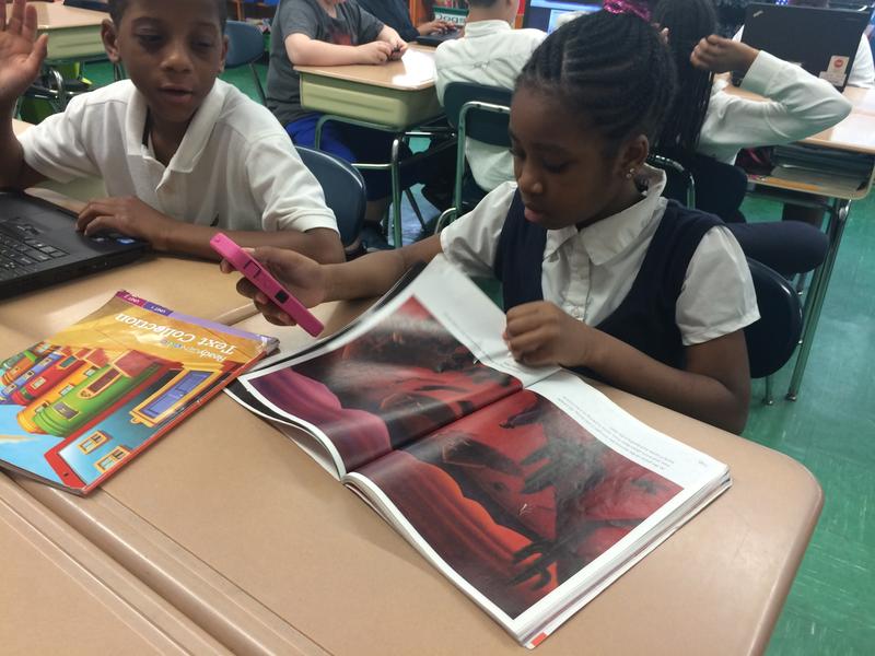 Amy, a fourth-grader at P.S. 129, references reading material before participating in a class Q&A on her cellphone.