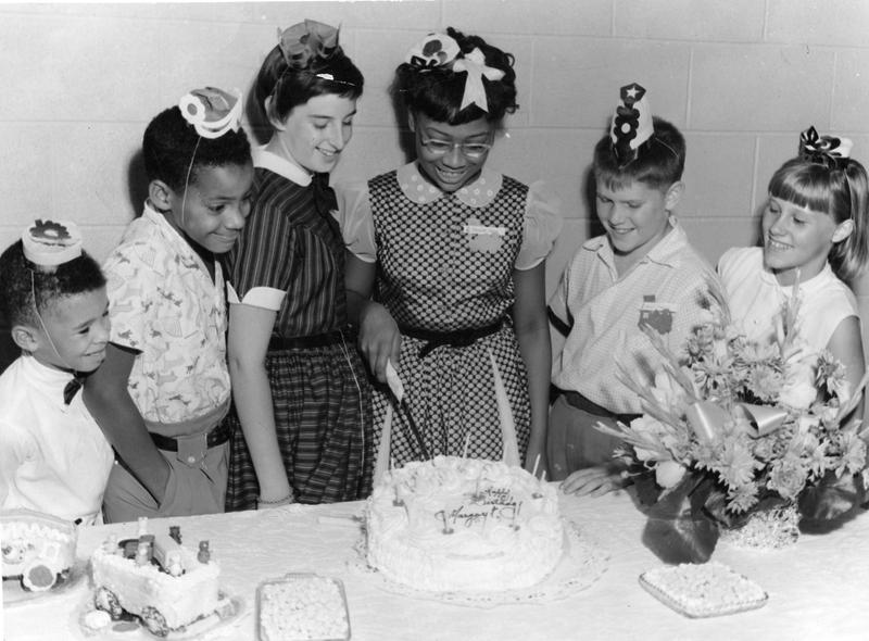 Portrait of a group of children at birthday party where one is about to cut the cake, upon which is written 'Happy Birthday Margaret,' 1959.