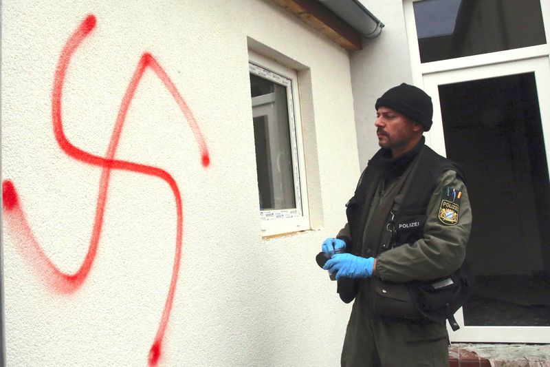 A police investigator stands in front of a house for asylum seekers and refugees that was damaged in an arson and vandalism attack in Vorra, in southern Germany near Nuremberg on December 12, 2014.