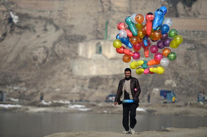 An Afghan man carries balloons for sale as he walks at Shuhada Lake in Kabul on February 10, 2014. Despite economic improvement in the last decade, Afghanistan is still extremely poor.