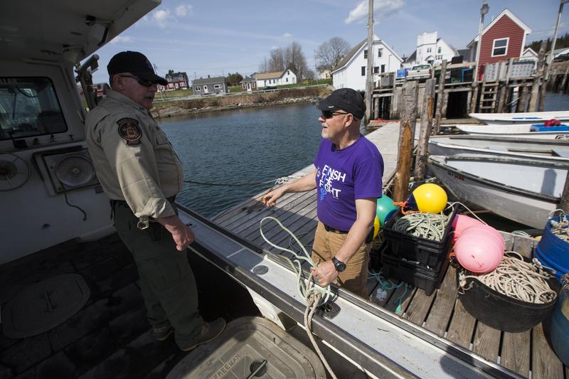 Maine Marine Patrol specialist Mark Murry speaks with lobsterman Brian Cates, right, in Cutler, Maine, May 7, 2015.