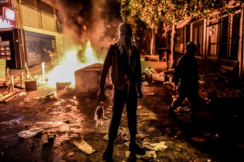 A masked Kurdish militant holds a molotov cocktails in front of a burning barricade during clashes with Turkish police on August 27, 2015 in the Gazi district of Istanbul.