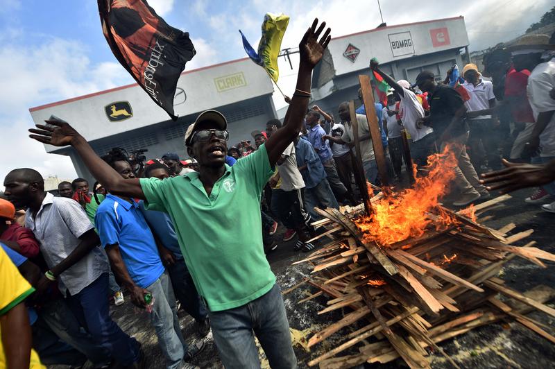 Protesters run around the fire while perform a voodoo ceremony prior a march in Port-au-Prince, on January 24, 2016 to demand the resignation of Haitian President, Michel Martelly.