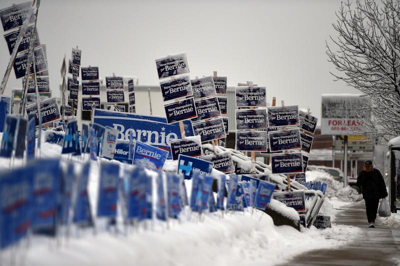 An elderly man walks past campaign signs of US Democratic presidential candidates Hillary Clinton and Bernie Sanders in Manchester, New Hampshire, on February 5, 2016.