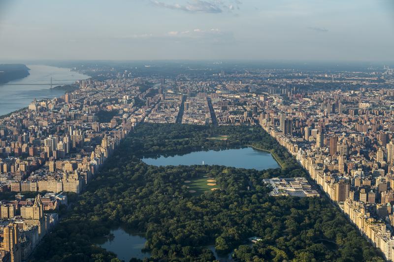 Aerial over Central Park looking uptown in Manhattan in NYC, Jacqueline Kennedy reservoir, George Washington Bridge, Hudson River, and buildings surrounding.