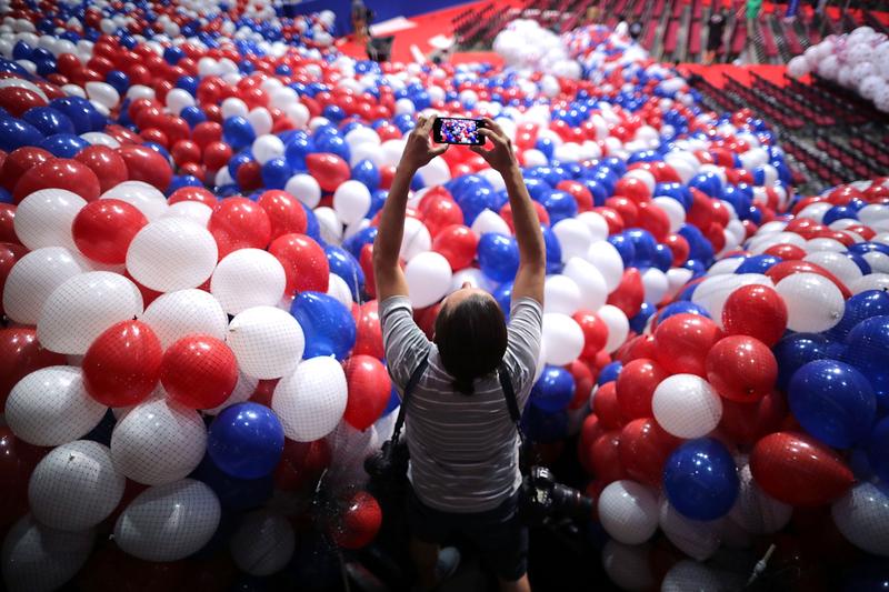 A news photographer makes images of nets filled with thousands of red, white and blue balloons before they are lifted into the ceiling of the Quicken Loans Arena July 15, 2016 in Cleveland, Ohio.