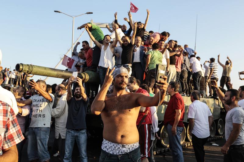 Supporters of Turkish President Recep Tayyip Erdogan wave flags as they capture anTurkish Army APC after soldiers involved in the coup surrendered on Bosphorus bridge on July 16, 2016 in Istanbul.